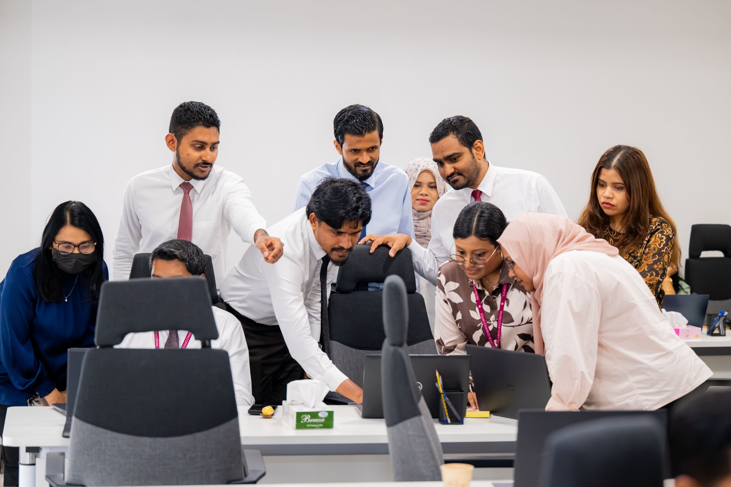 The Future Institute team gathered around a laptop, working together in the office