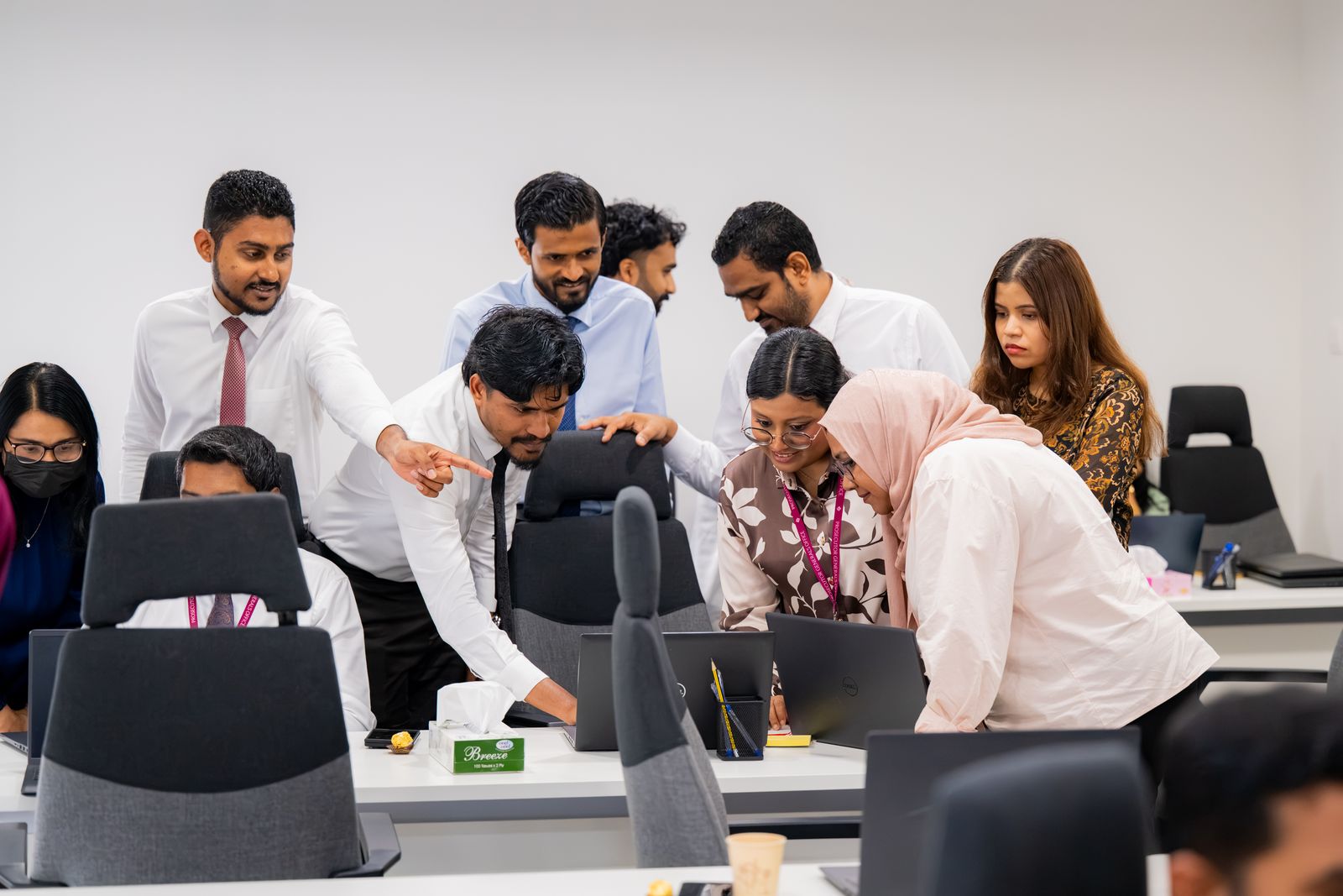 Participants gathered around a laptop during a hands-on activity