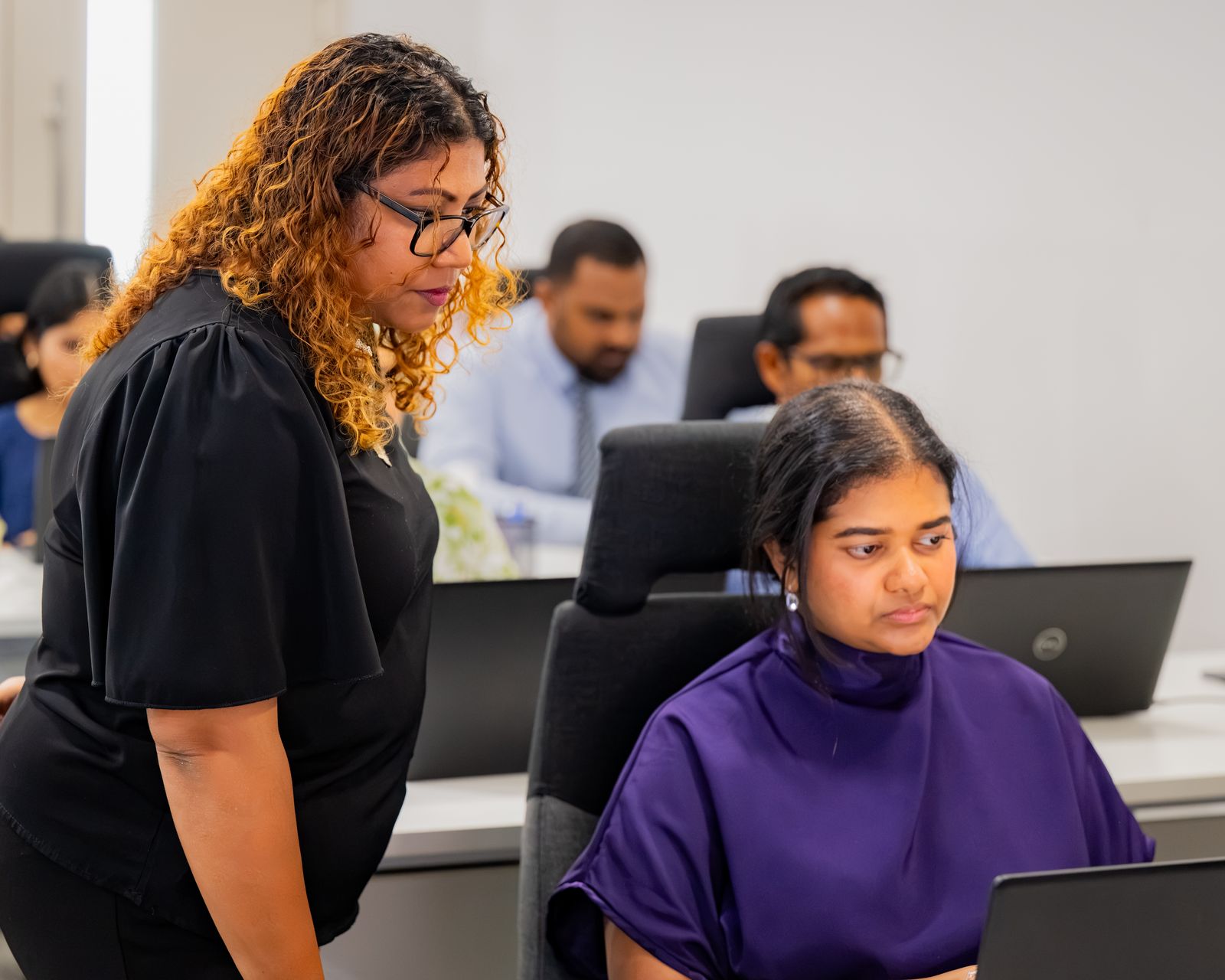 A Future Institute trainer supporting a participant working on a laptop