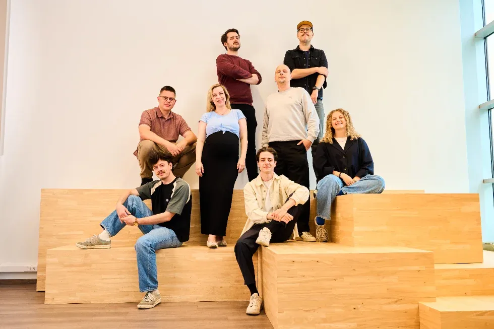 The Unmute You team posing together on wooden steps in a bright studio.