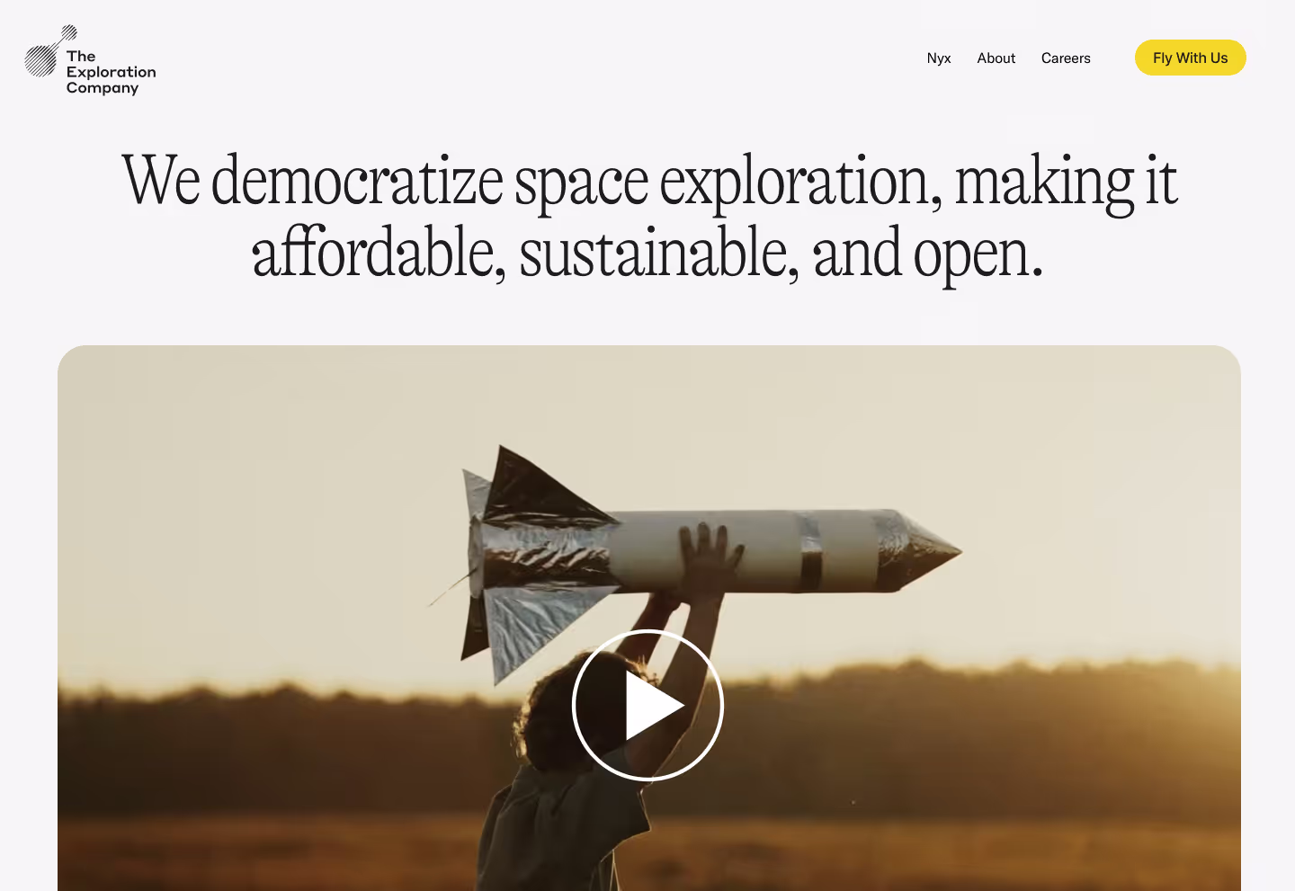 Child holding a homemade rocket model above their head at sunset in an open field.
