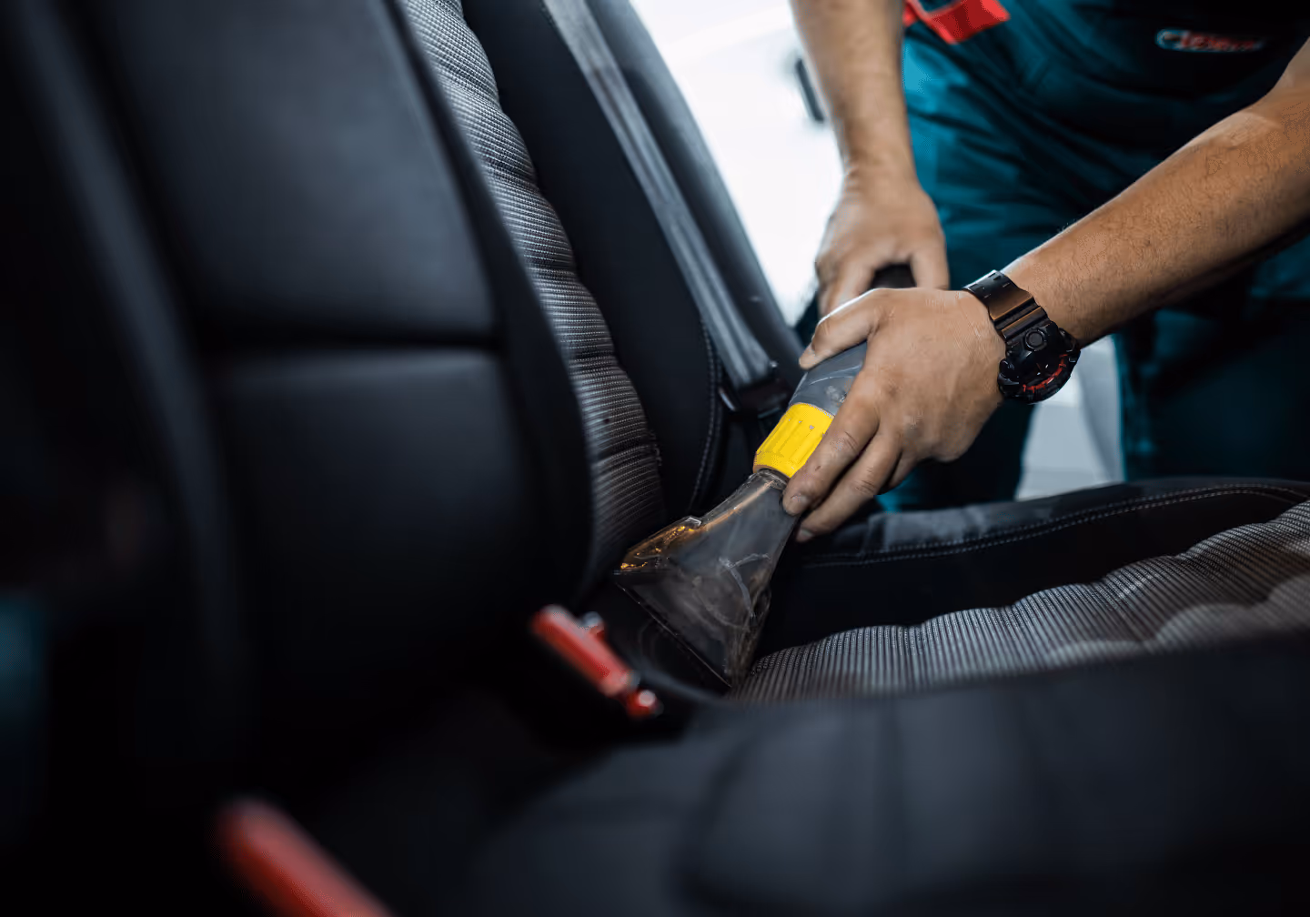 Ein Fahrzeugsitz wird gründlich und professionell mit einem Sauger gesaugt. 