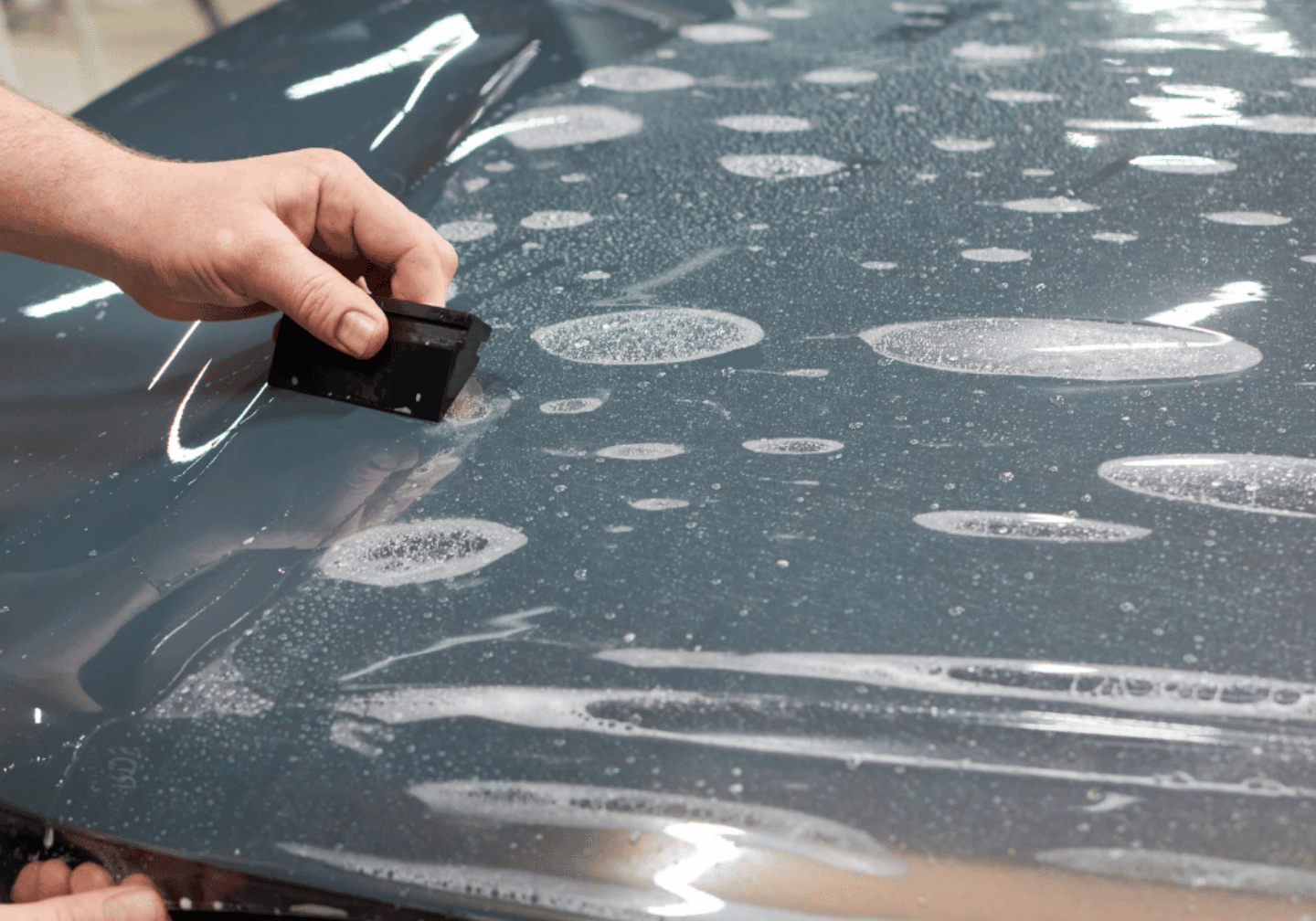 Ein dunkler Wagen wird professionell foliert.