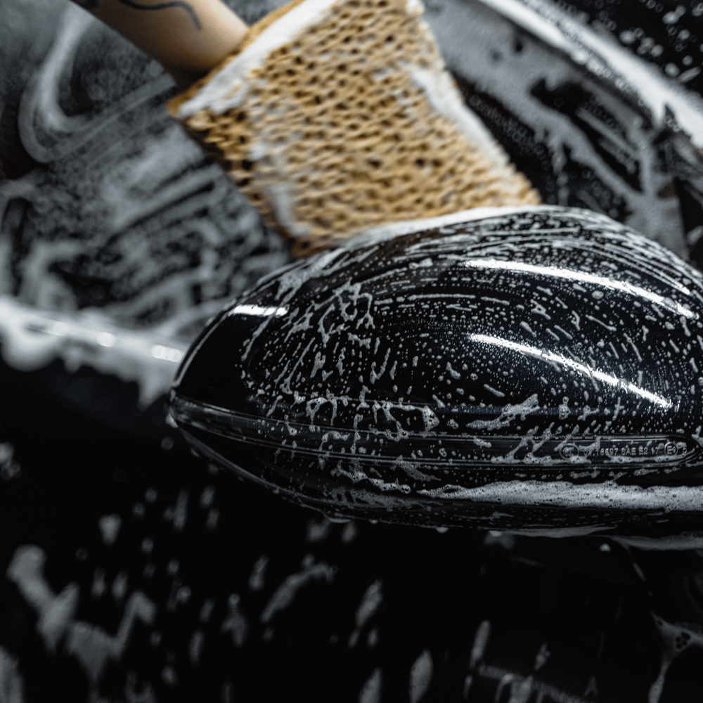 Schwarzes Fahrzeug wird mit viel Schaum eingeseift und gewaschen.