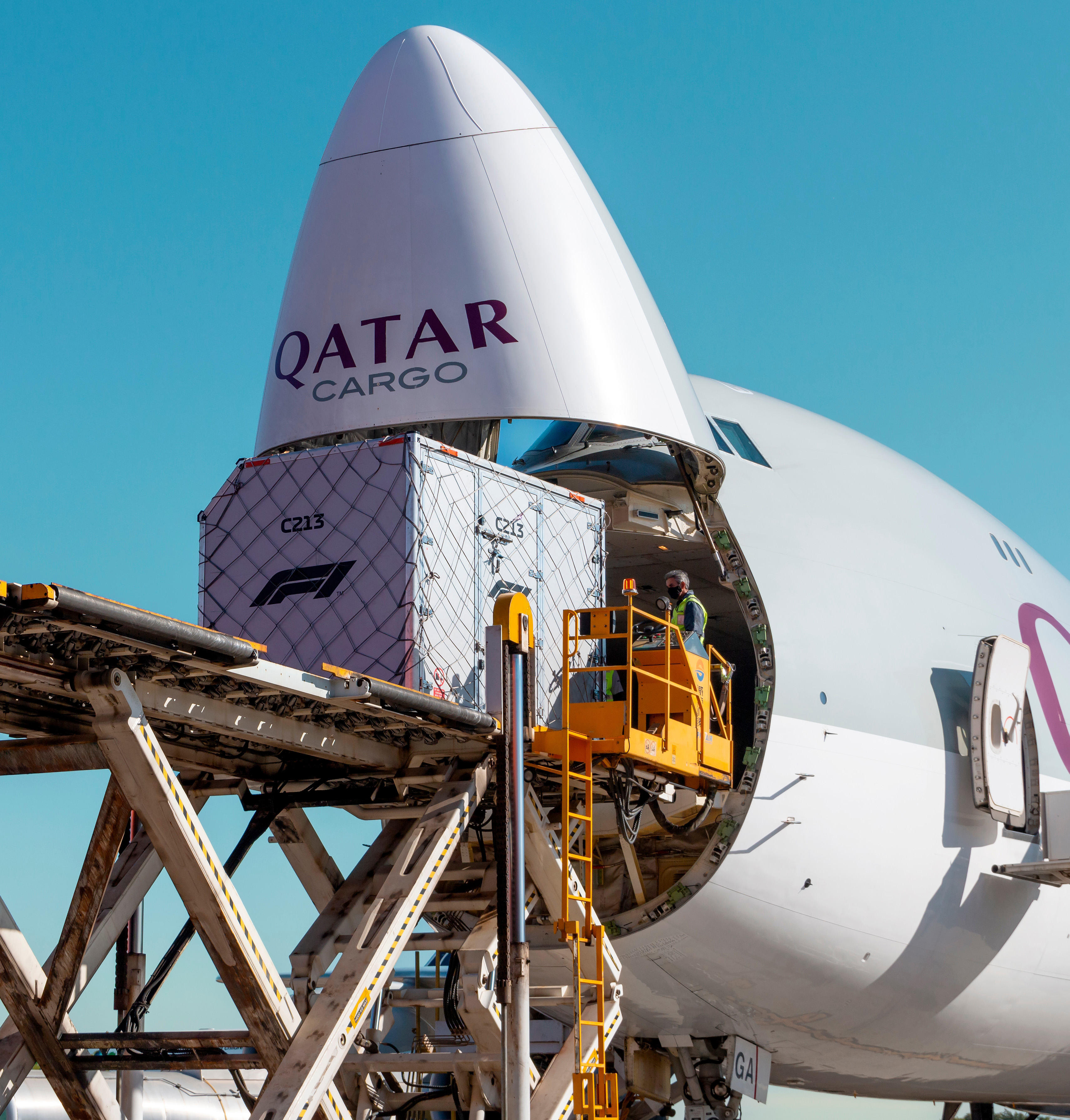 Frachtcontainer wird in eine geöffnete Nase eines Qatar Cargo Flugzeugs verladen.