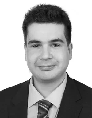 Portrait of a young man with short dark hair wearing a suit, dress shirt, and striped tie.