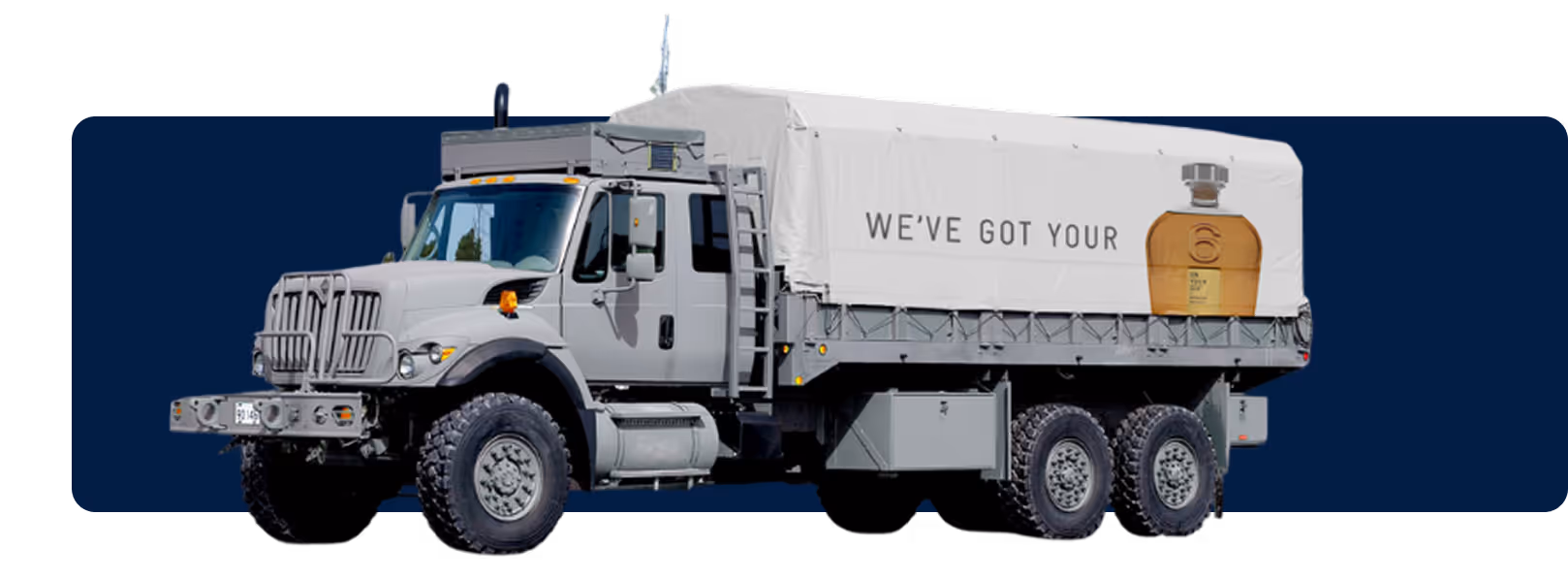 Military-style gray truck with a branded white tarp that reads 'WE’VE GOT YOUR' alongside a bottle of On Your 6 whiskey