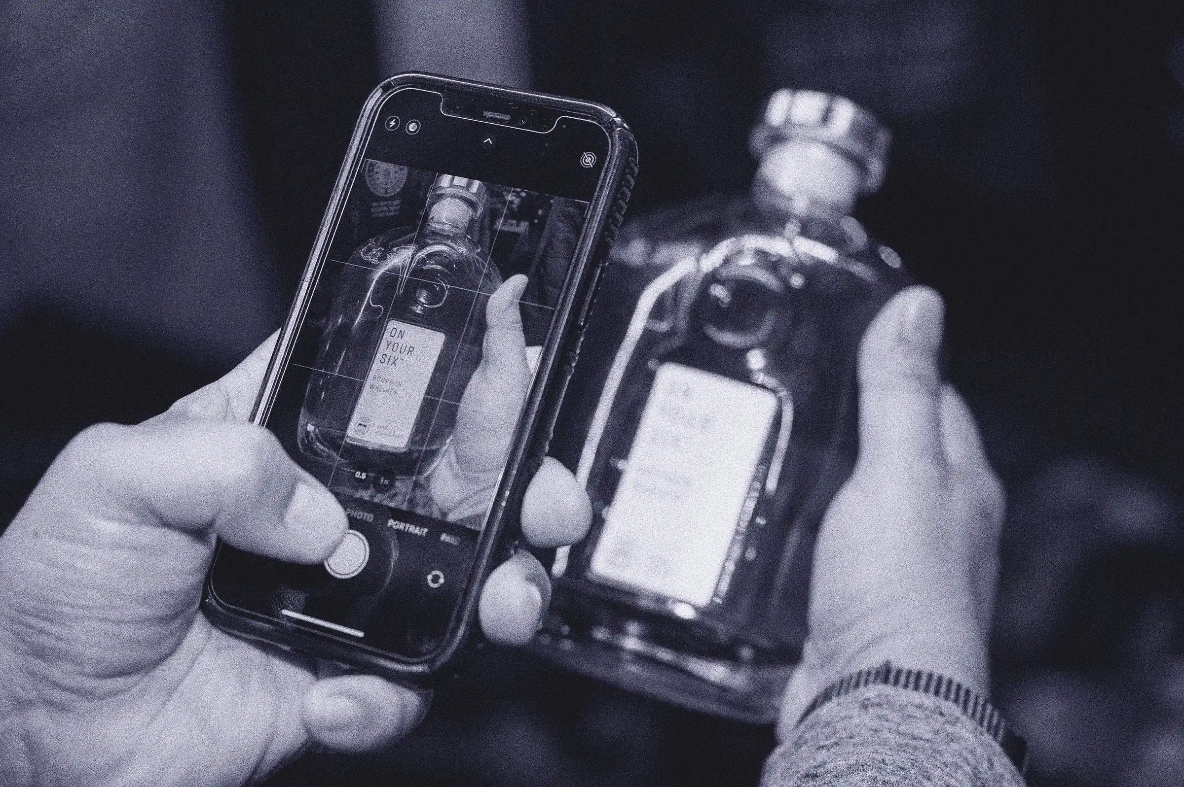 A person holding a cell phone with a picture of a bottle of liquor.