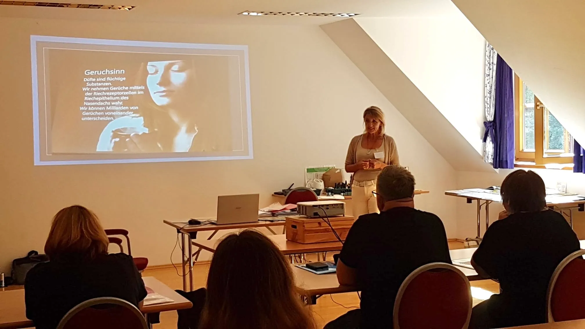 Lisa Walder hält eine Präsentation über den Geruchssinn vor Publikum in einem Klassenzimmer mit Projektor und Laptop.