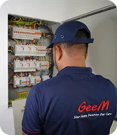 Electrician inspecting a complex electrical panel with wiring and circuit breakers.