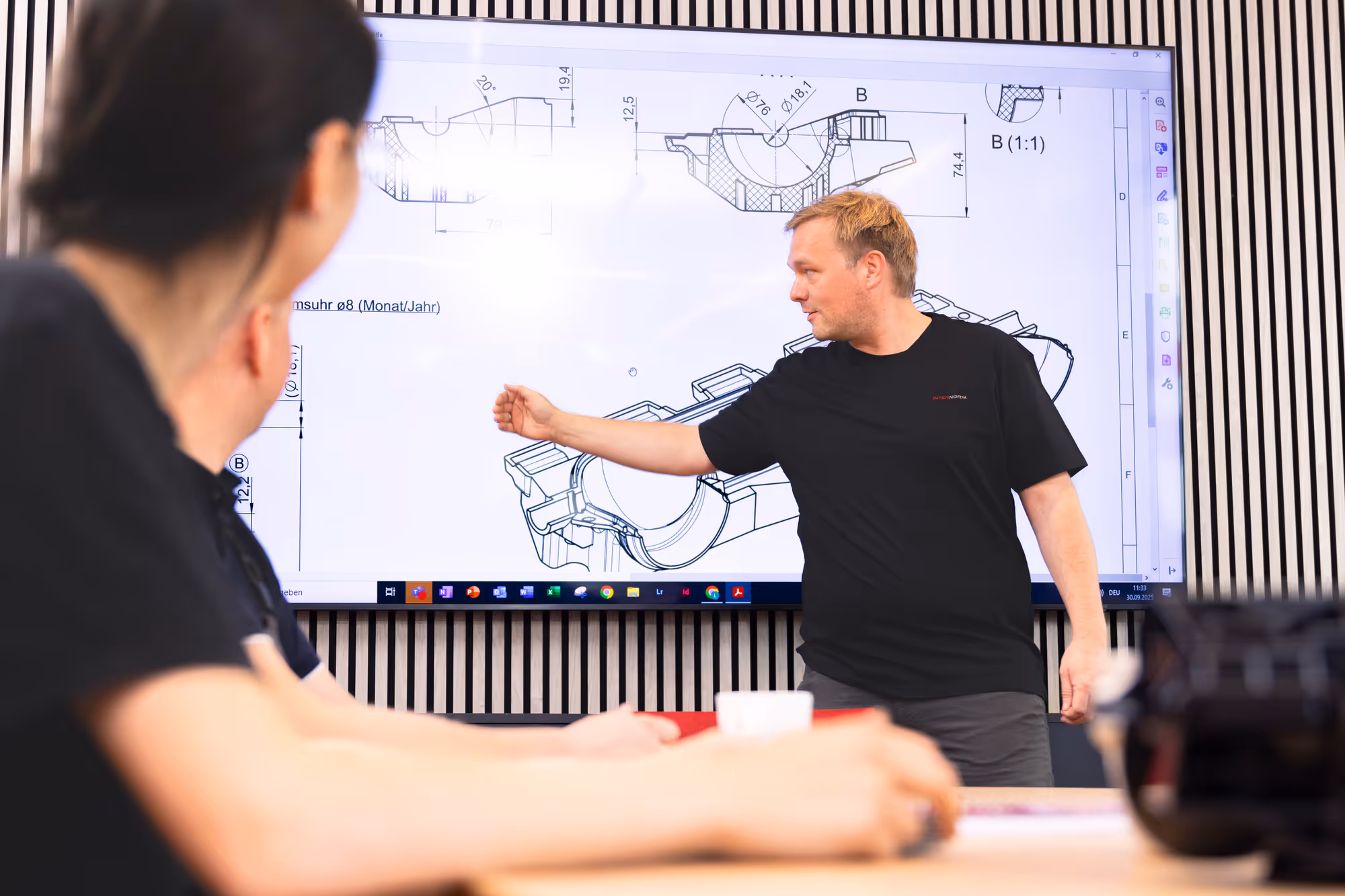 Kollege präsentiert Konstruktionszeichnungen auf einem Bildschirm