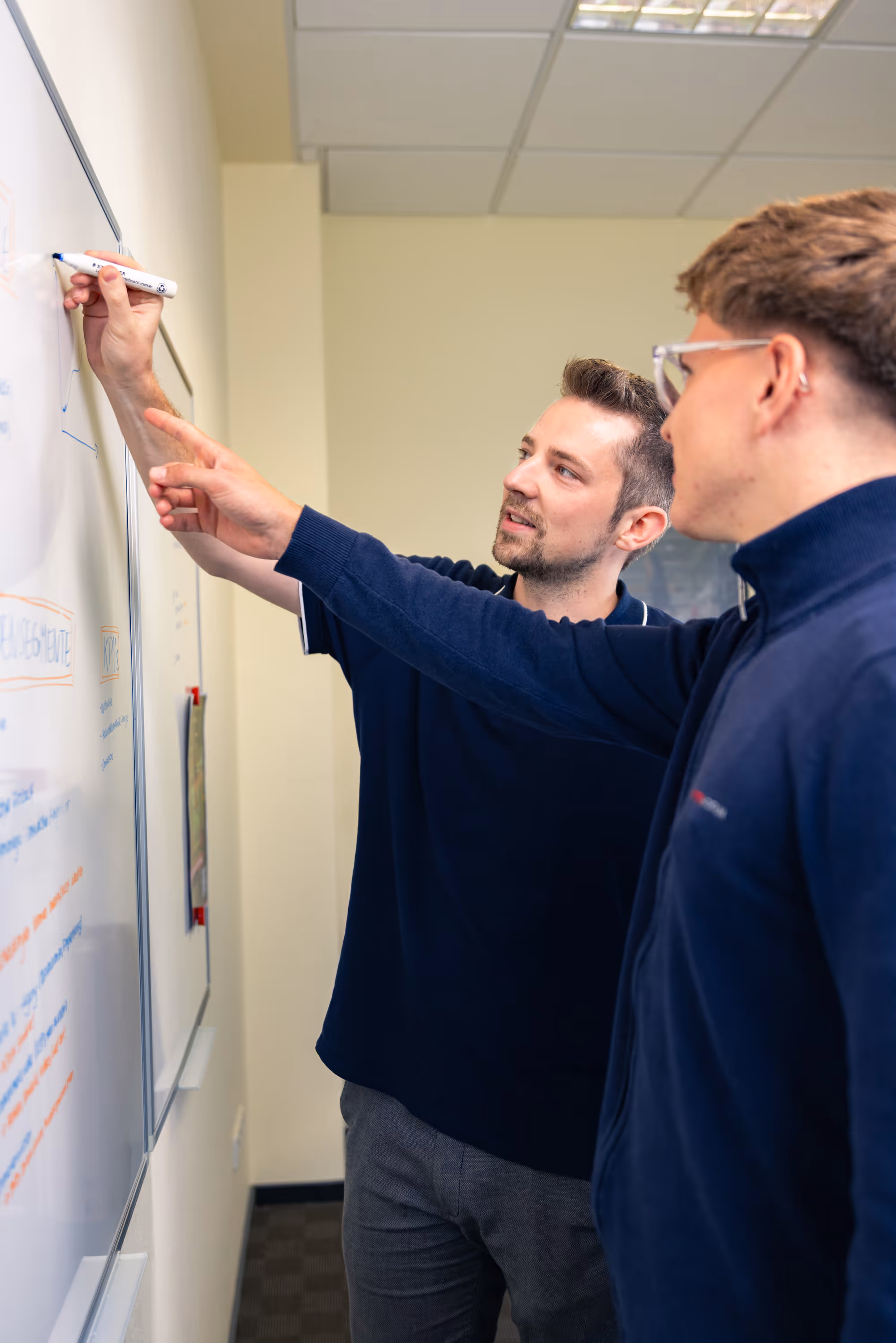 2 colleagues on a whiteboard during a meeting
