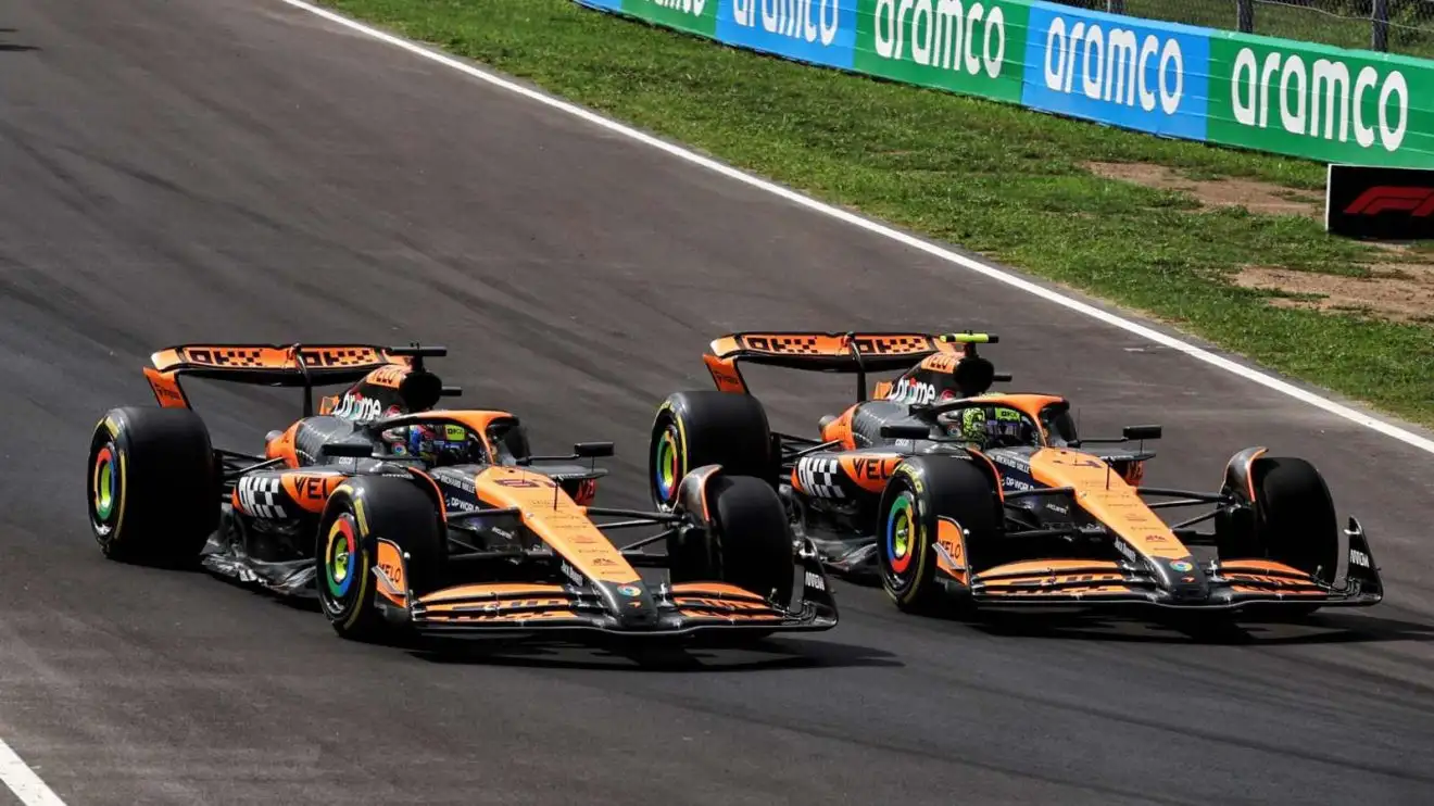 Oscar Piastri and Lando Norris side by side racing in their McLaren F1 cars.