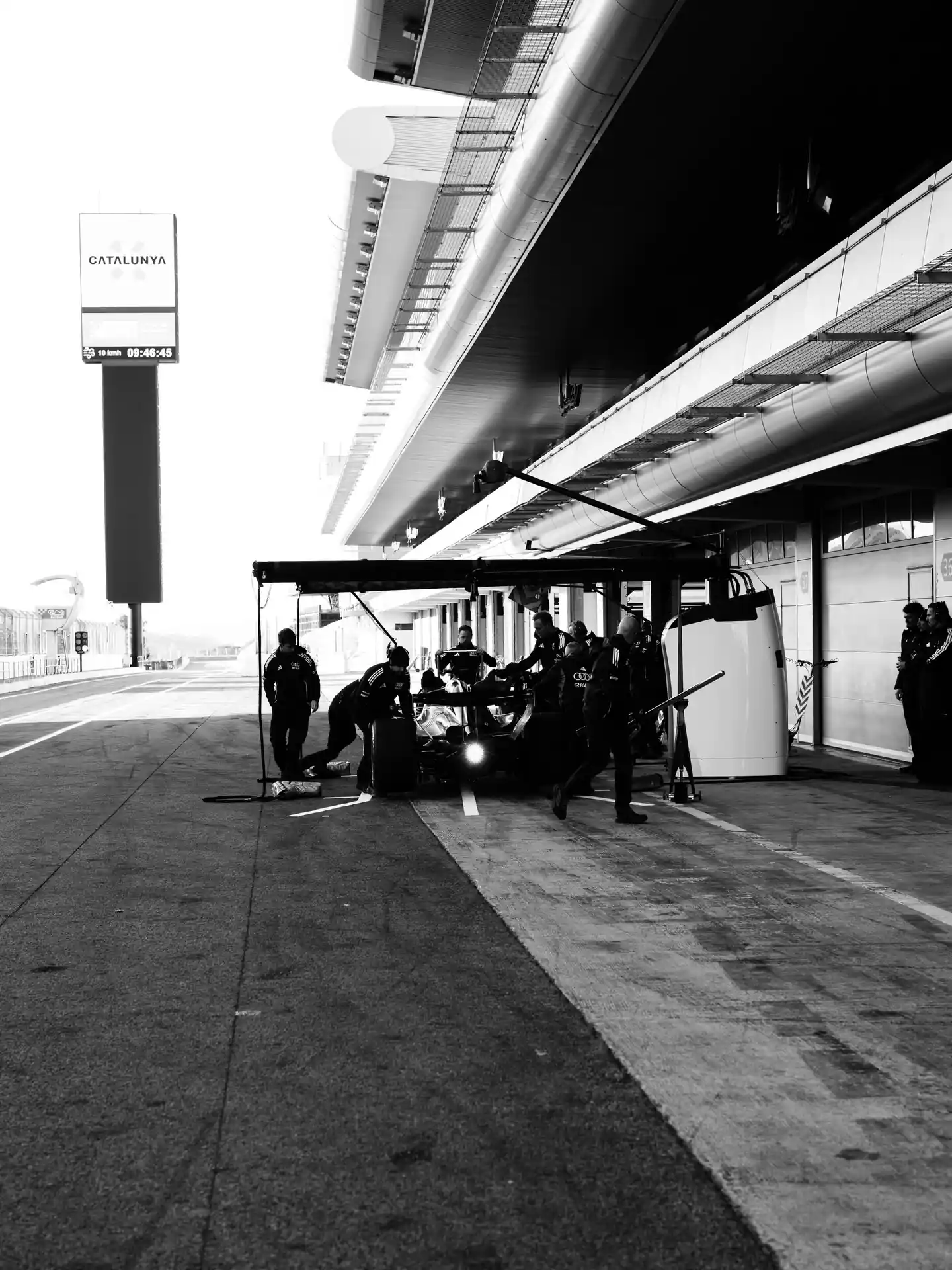 Black and white image of Audi's R26 F1 car in the pits at Barcelona.