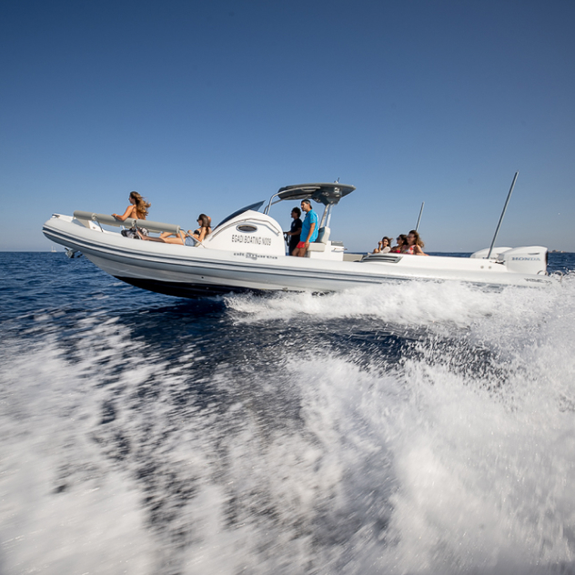 White motorboat speeding on blue sea with seven people enjoying a sunny day on board.