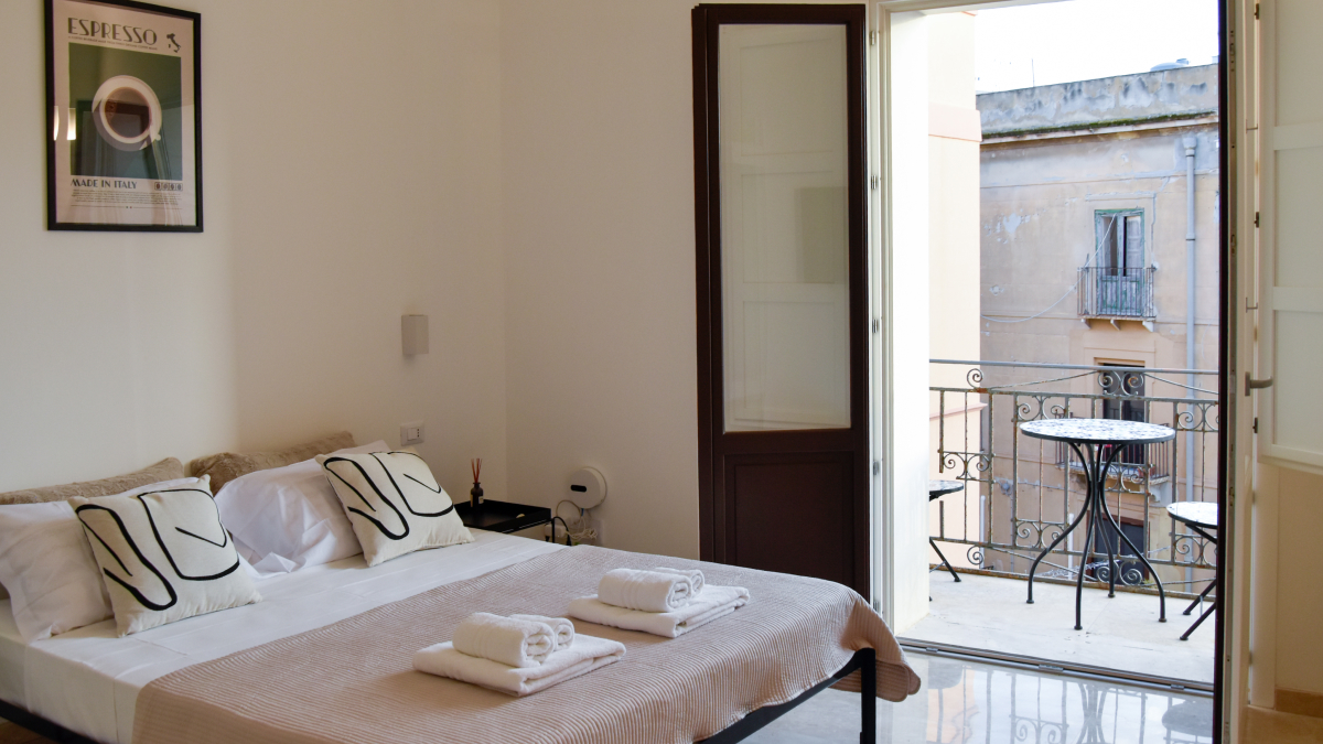Sypialnia w apartamencie Espresso w Trapani z wyjściem na balkon przy Via Libertà, jasne wnętrze i łóżko małżeńskie