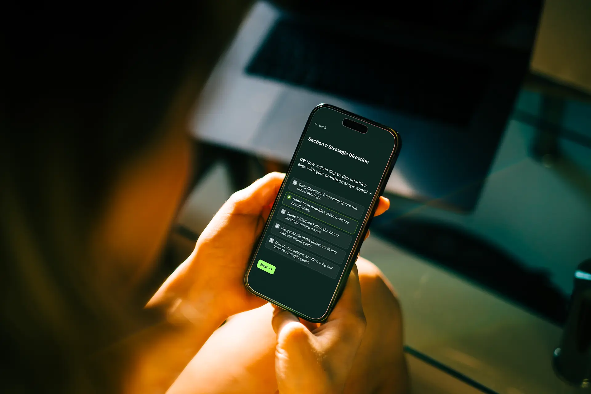 Person holding a smartphone displaying a survey question about day-to-day priorities aligning with brand's strategic goals.