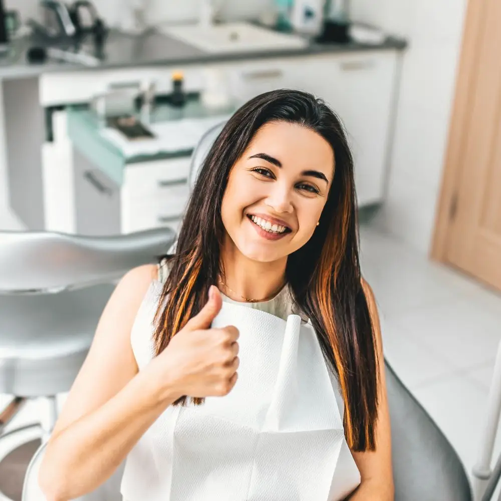a woman sitting in a chair giving a thumbs up