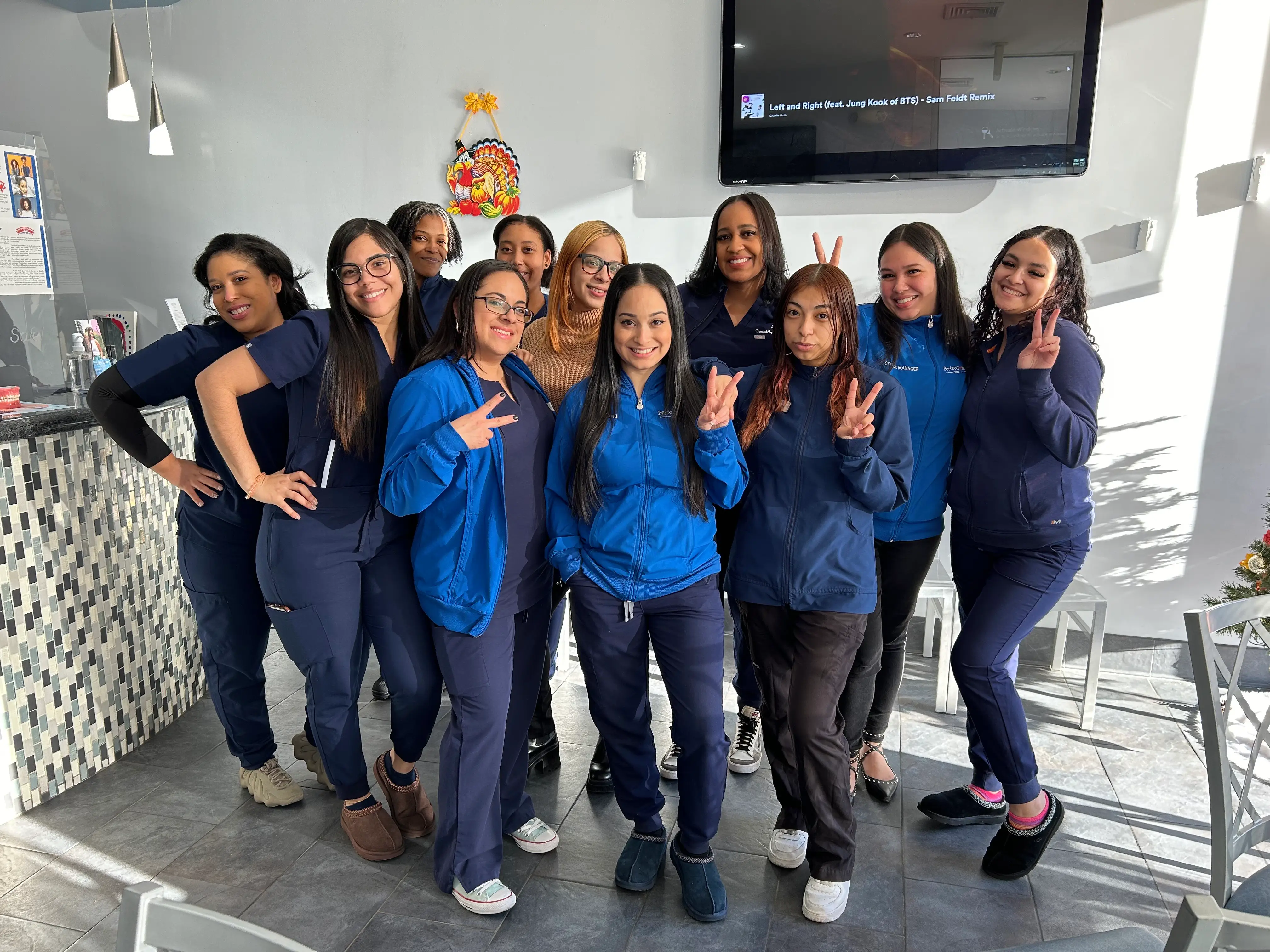 Group of people in blue uniforms posing in a dental office