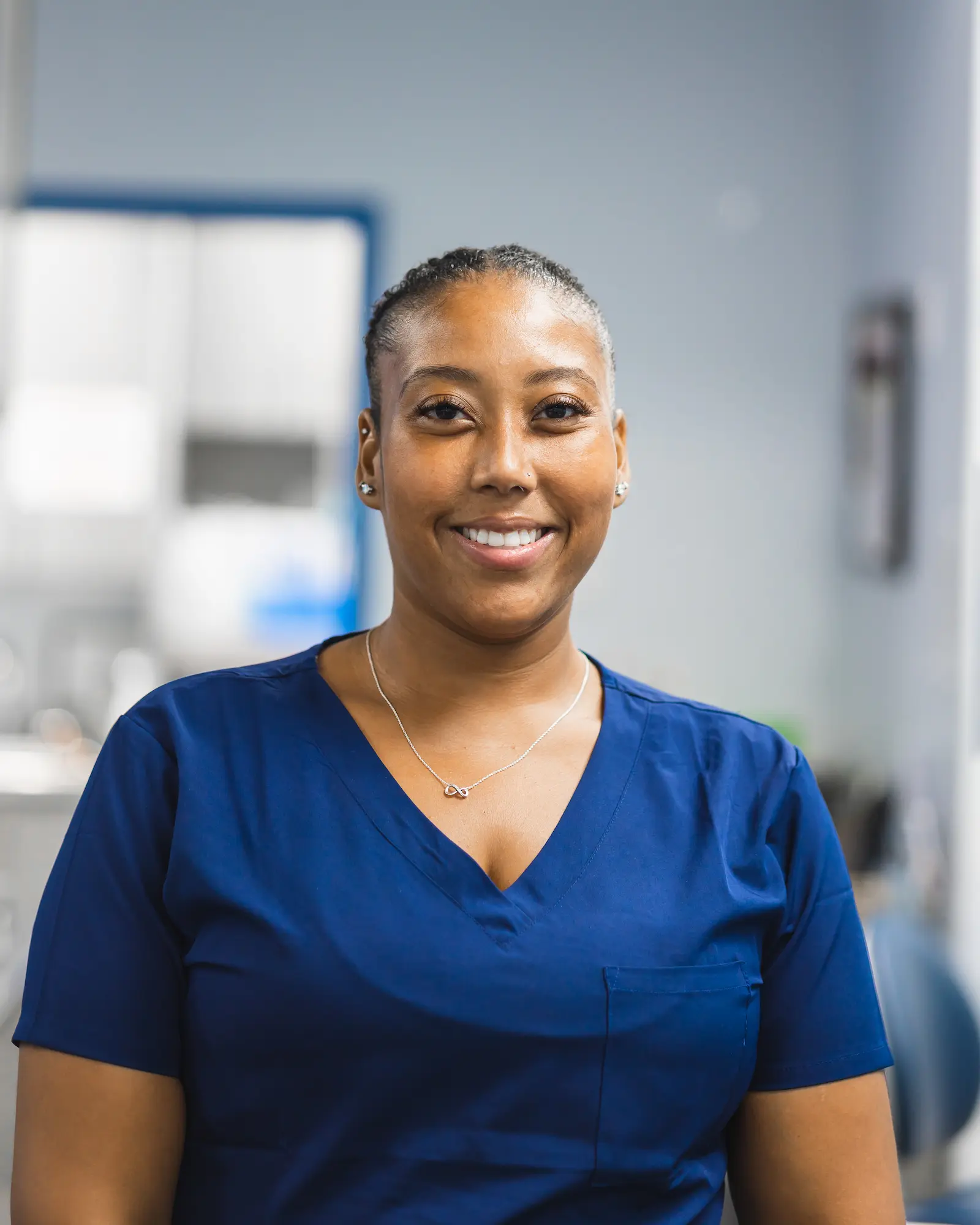 a woman in a blue scrub top smiles at the camera