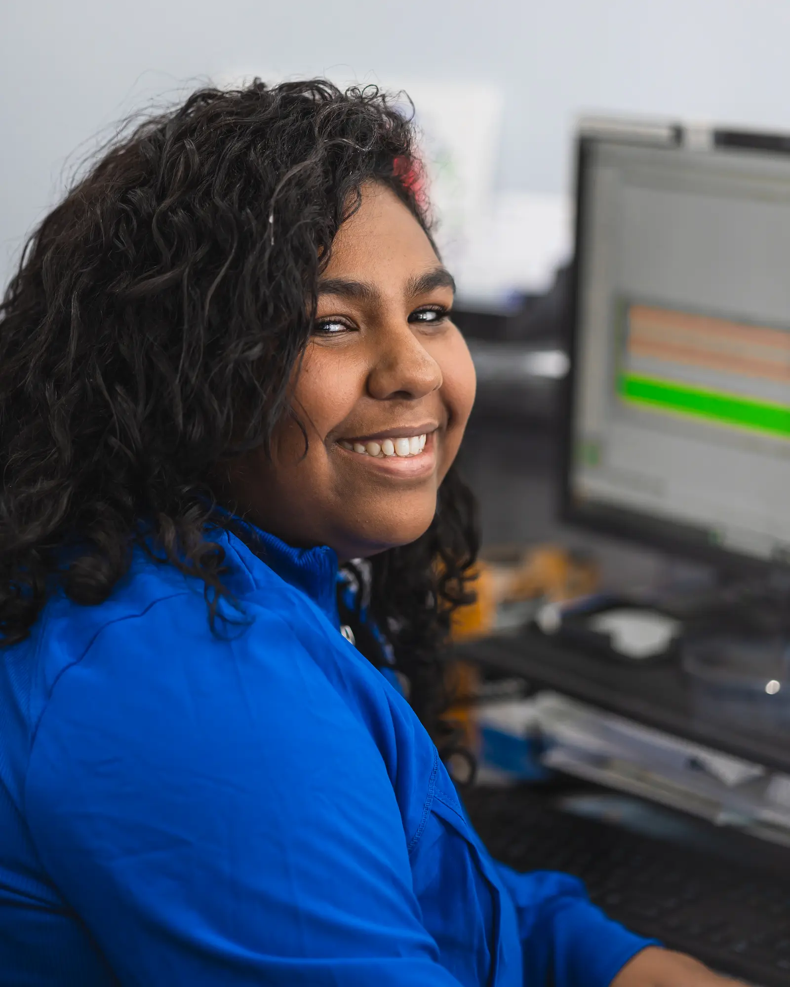a smiling woman sitting in front of a computer