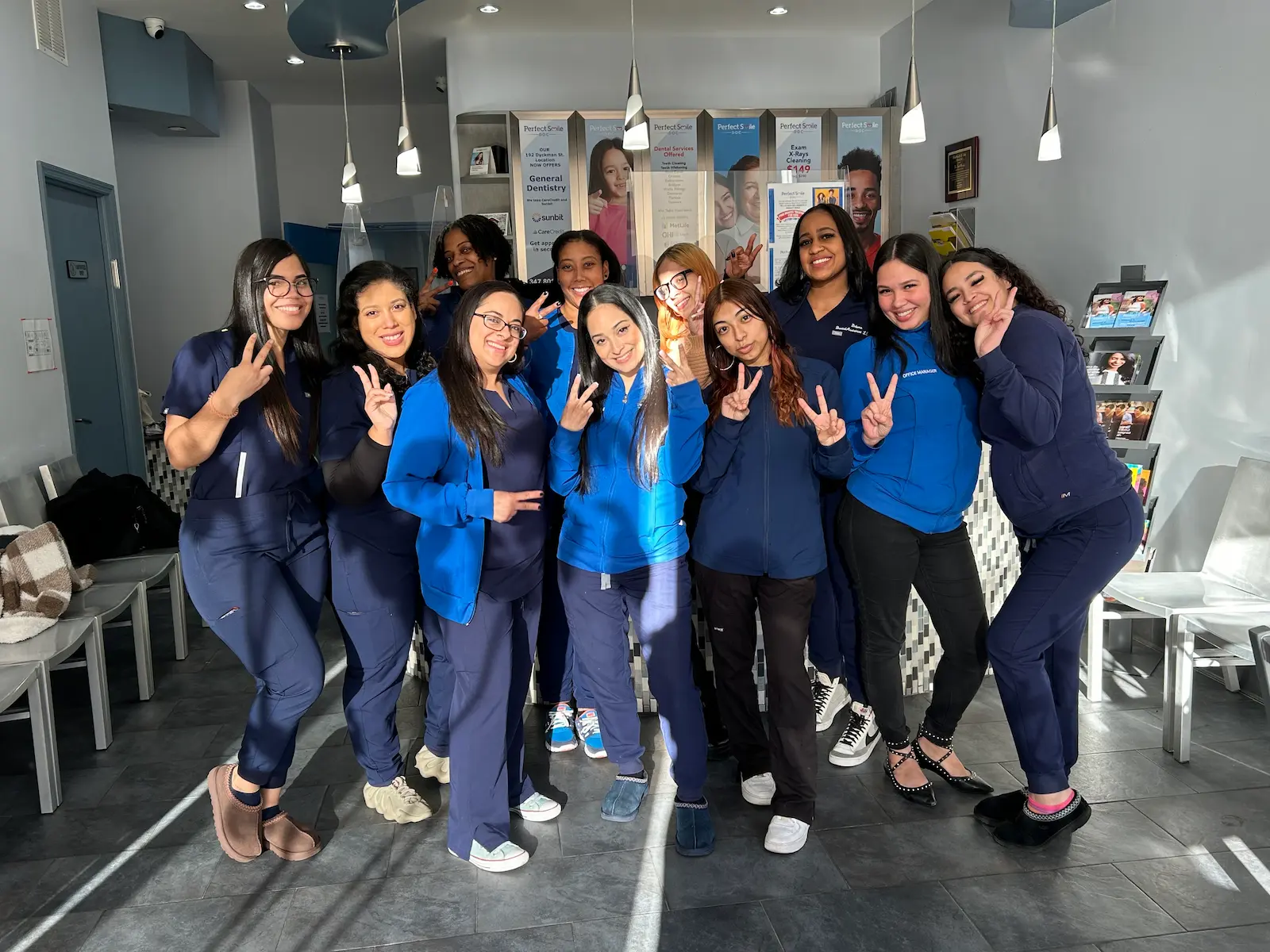 Group of people in blue uniforms posing in a dental office