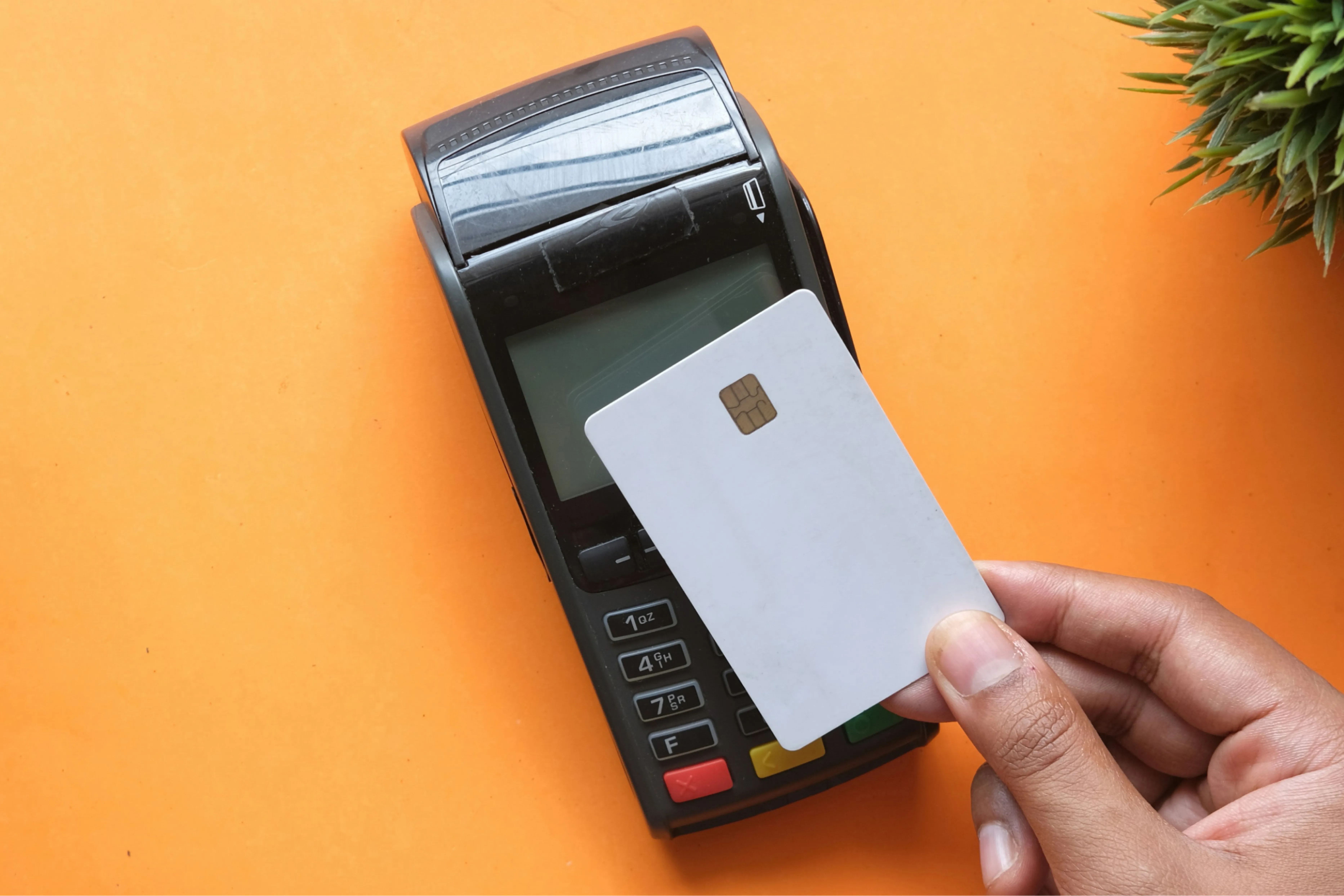 A hand holding a bank card on a pinterminal