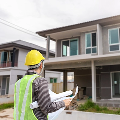 Inspector wearing safety gear reviewing plans in front of a recently repaired home, representing Peak Pro Home Services’ $99 post-repair inspection for buyers and sellers.