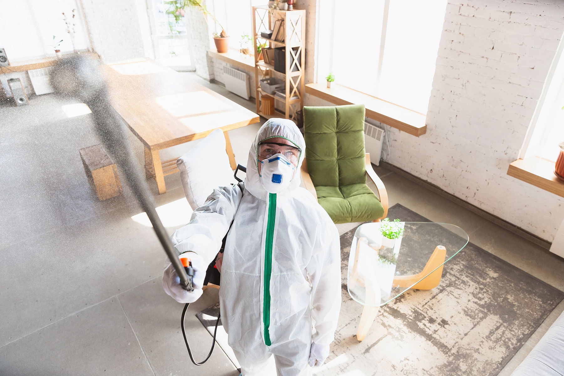 Technician in full protective gear spraying treatment inside a home during Peak Pro Home Services’ mold remediation process.