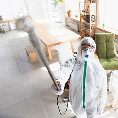 Technician in full protective gear spraying treatment inside a home during Peak Pro Home Services’ mold remediation process.