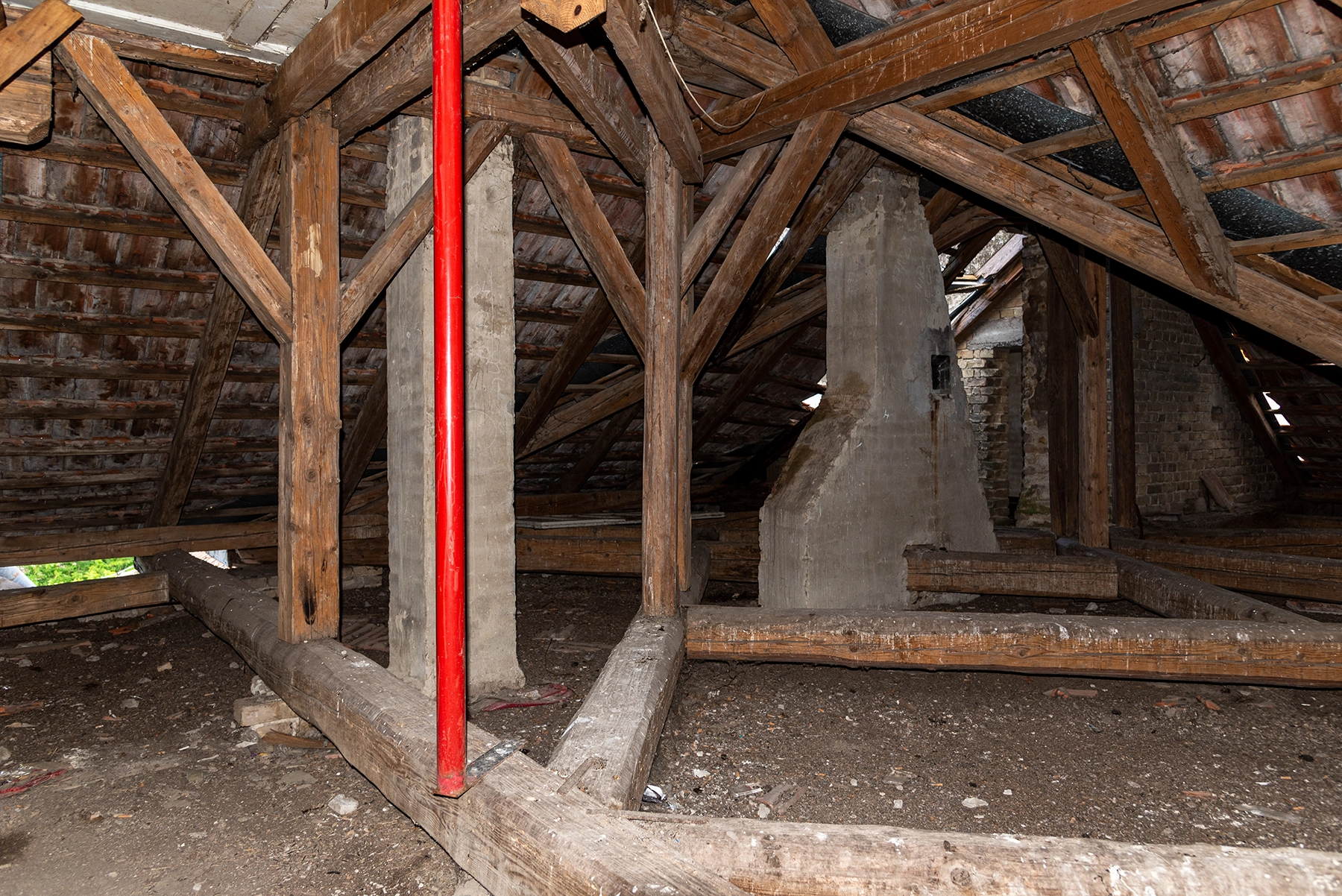 An unfinished attic with exposed wood beams, old insulation, and visible moisture damage, illustrating the type of crawl-space and attic repair work completed by Peak Pro Home Services in Yakima homes.