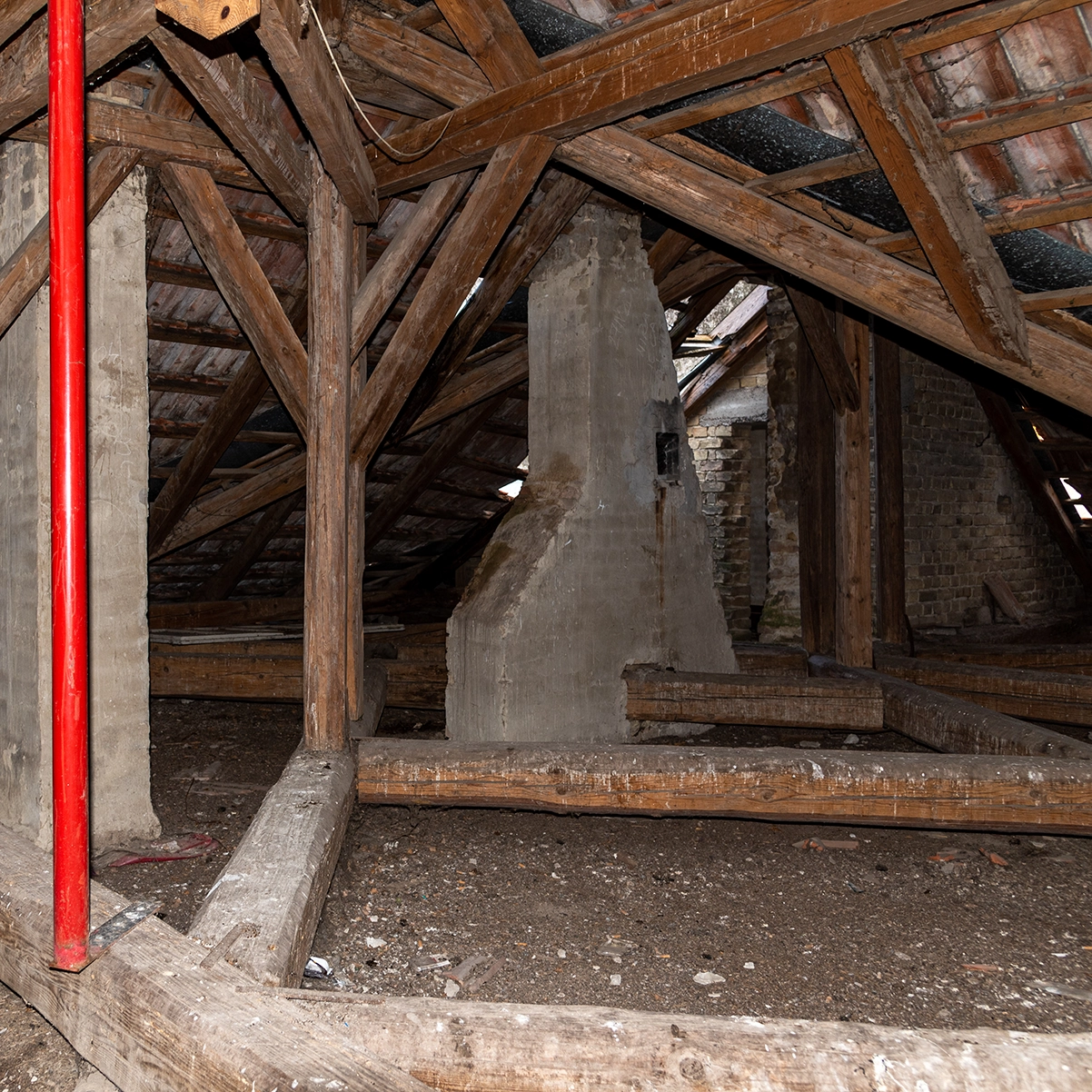 An unfinished attic with exposed wood beams, old insulation, and visible moisture damage, illustrating the type of crawl-space and attic repair work completed by Peak Pro Home Services in Yakima homes.