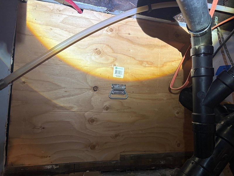 Large basement wall opening sealed with custom plywood panel and stainless steel wire mesh to prevent rodent re-entry.