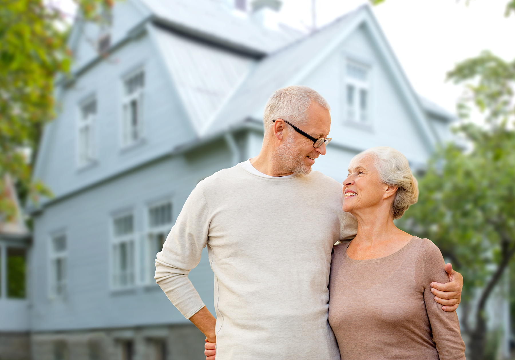 Senior couple standing outside their home, representing proactive home maintenance and long-term aging in place planning in Yakima.