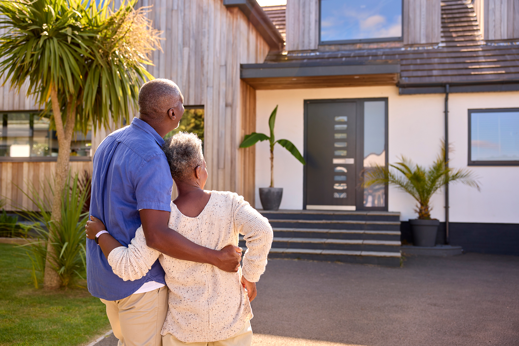 Older couple standing outside their modern home, representing proactive home maintenance planning and long-term home care in Yakima.
