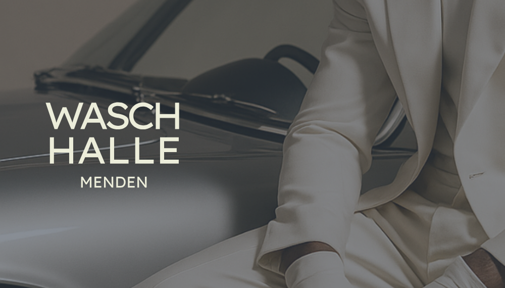 Ein gut gekleideter Mann lehnt sich vor ein Oldtimer