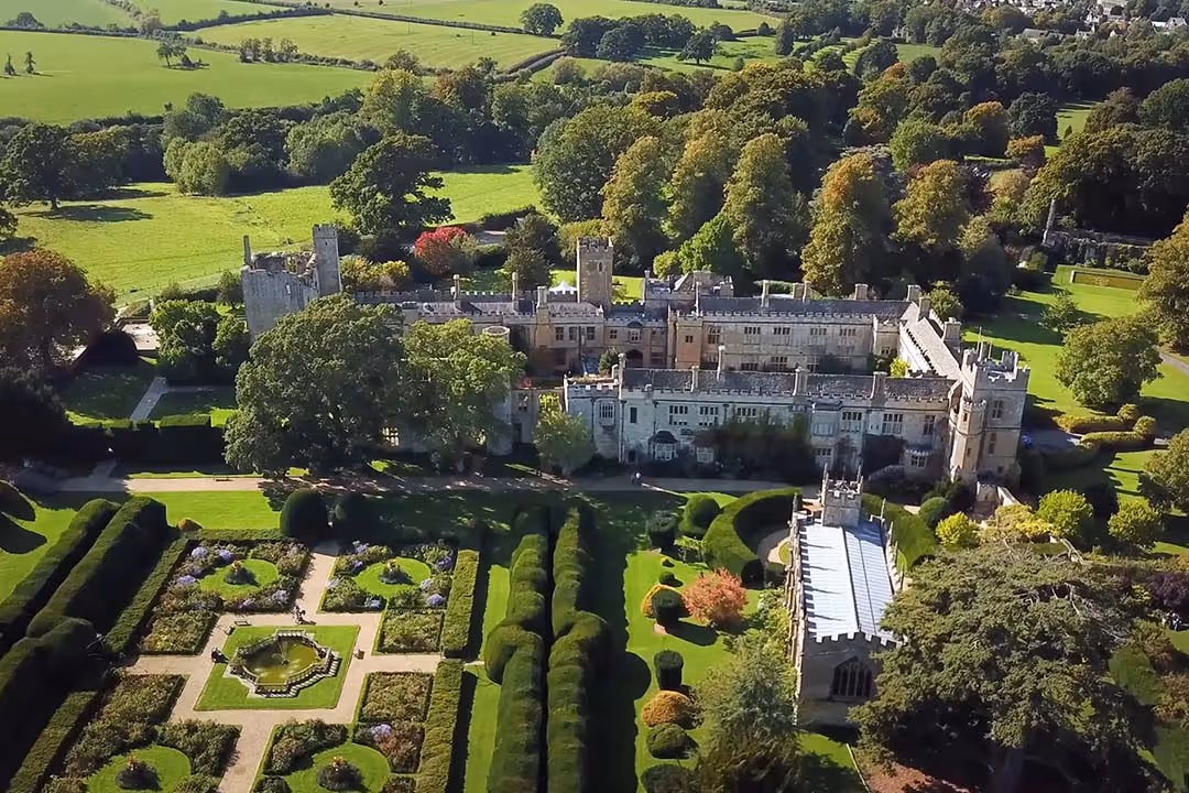 Aerial view of a historic castle surrounded by manicured gardens and lush green fields.