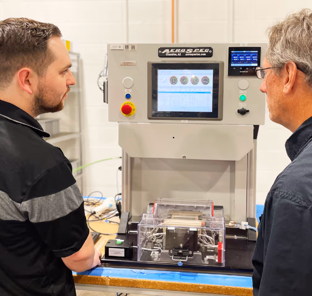 Two AeroSpec employees reviewing the components of a custom automated machine during inspection.