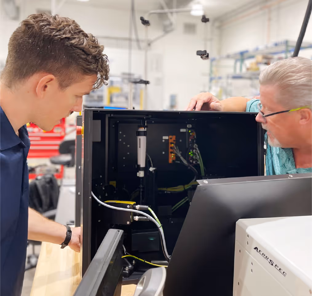 Two AeroSpec employees inspecting the interior of a fully custom automated machine.
