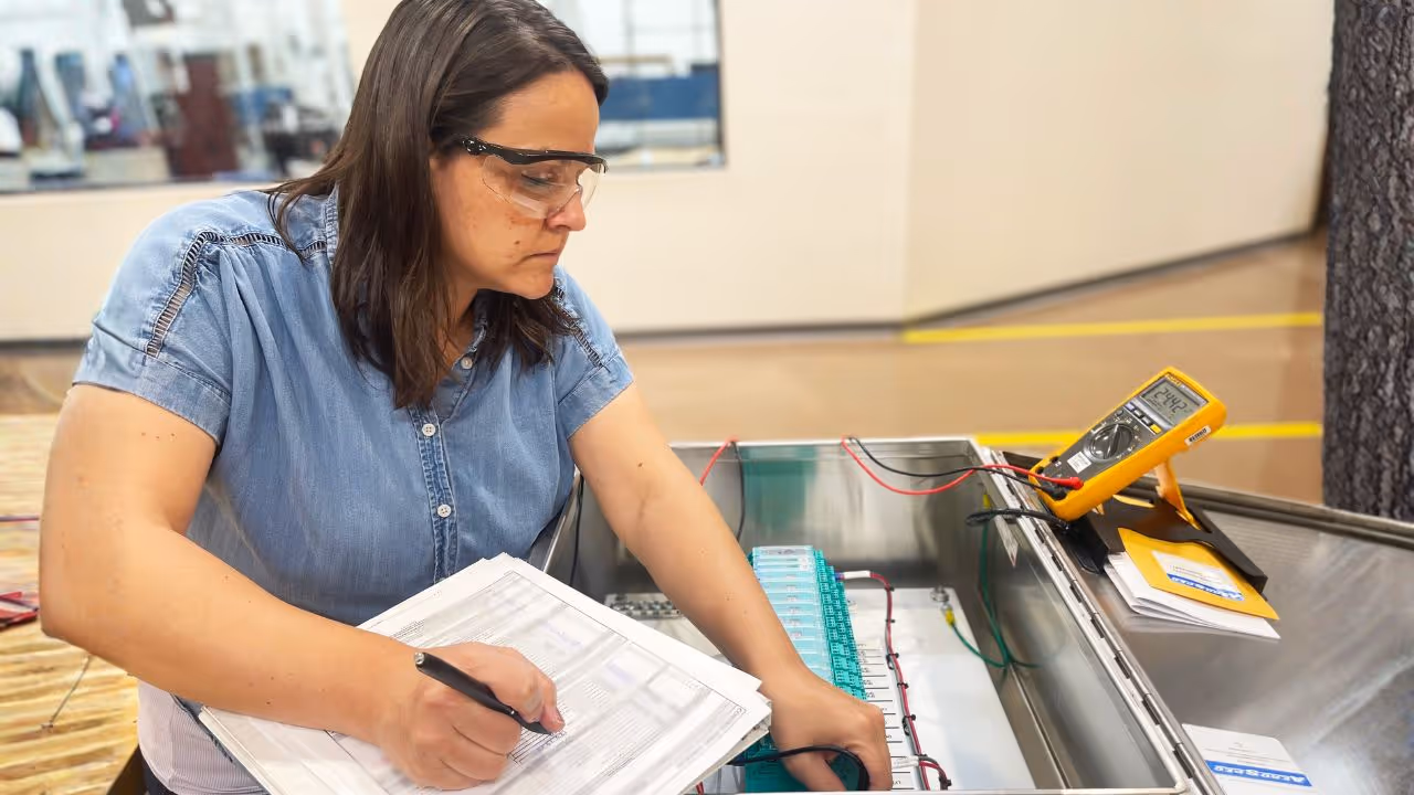 A controls engineer testing voltage inside of a completed industrial control panel.