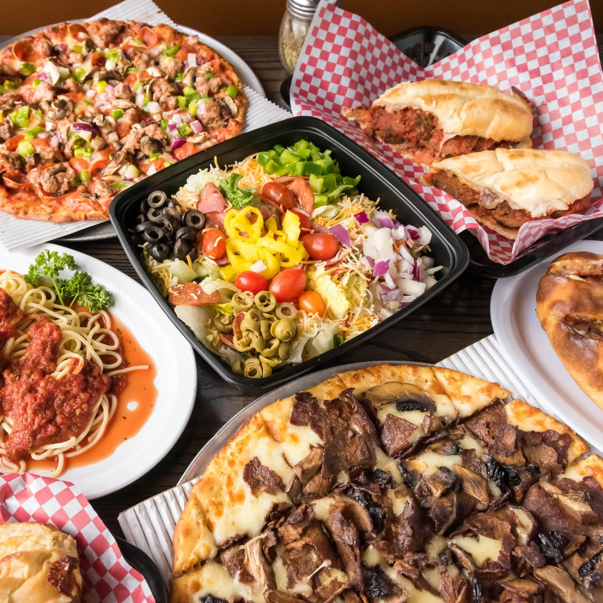 A table set with various pizzas and an assortment of other dishes, showcasing a colorful spread of food.