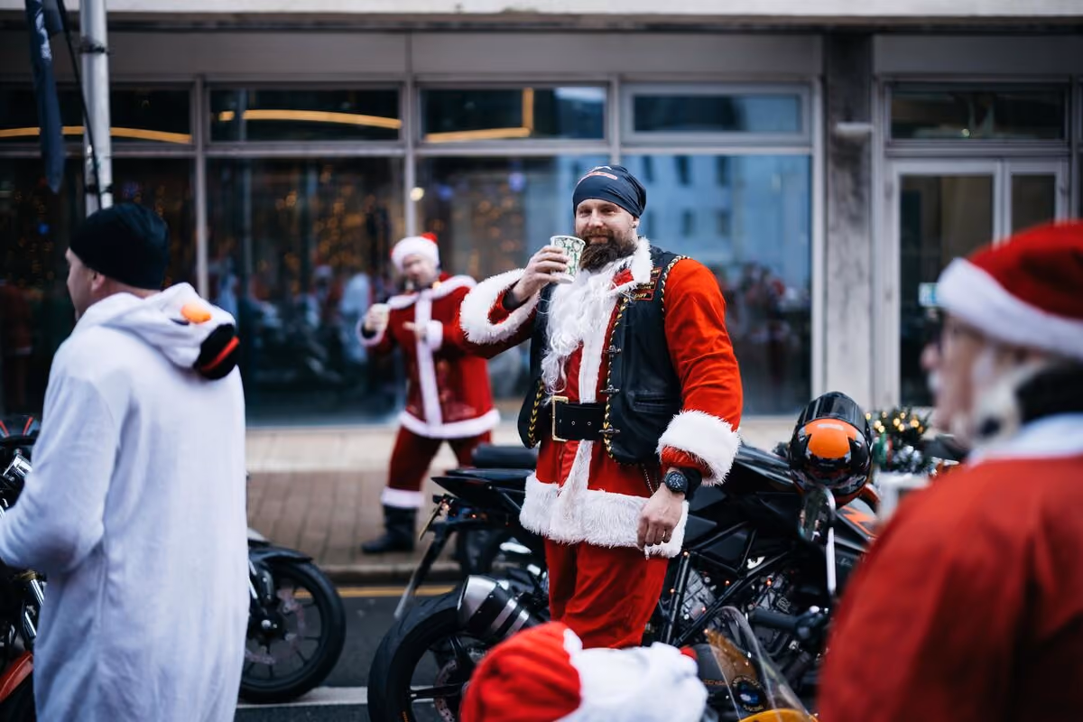 Riders in Santa suits gathering by their bikes