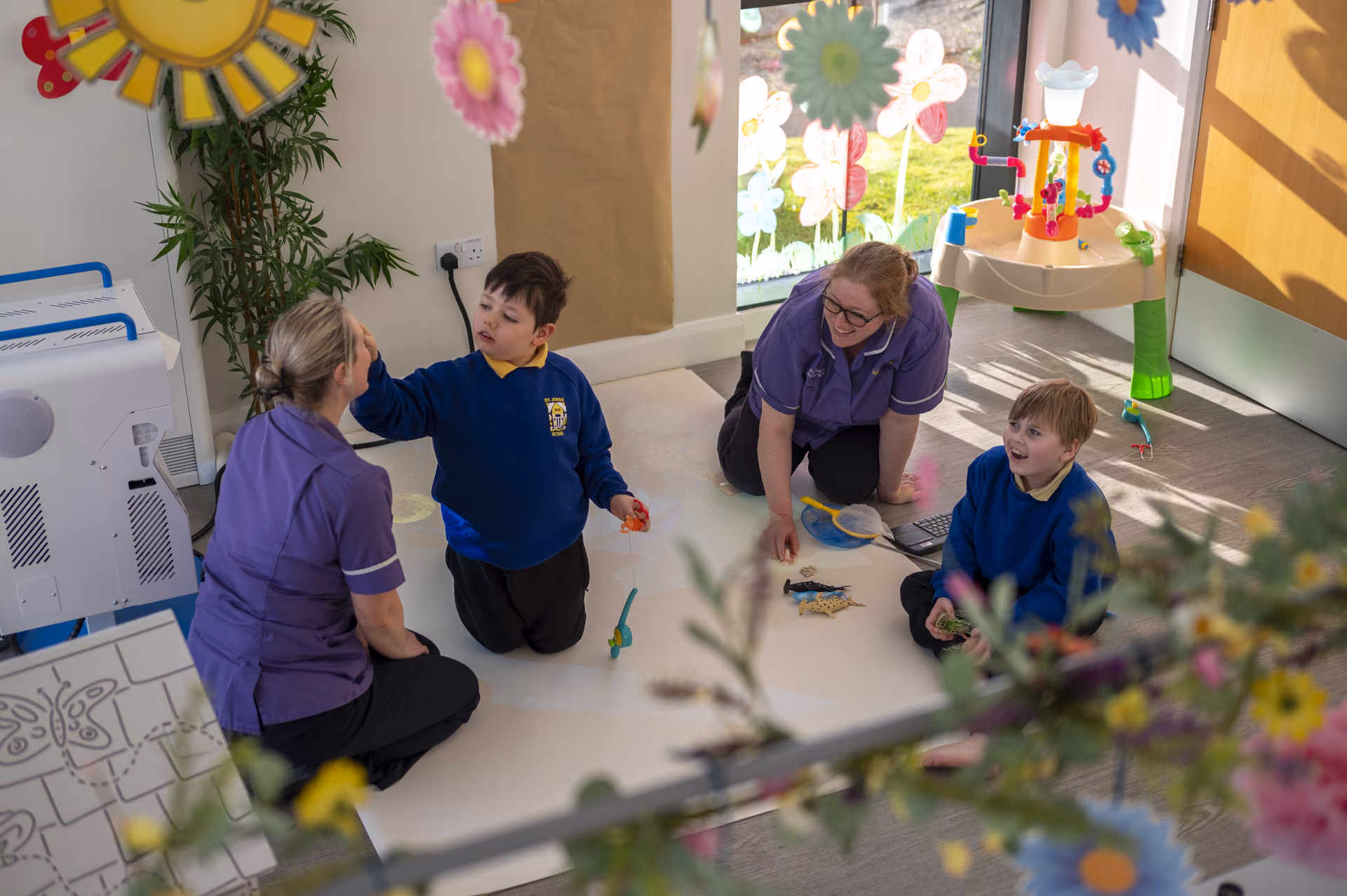 Rebecca House carers playing with children in the playroom
