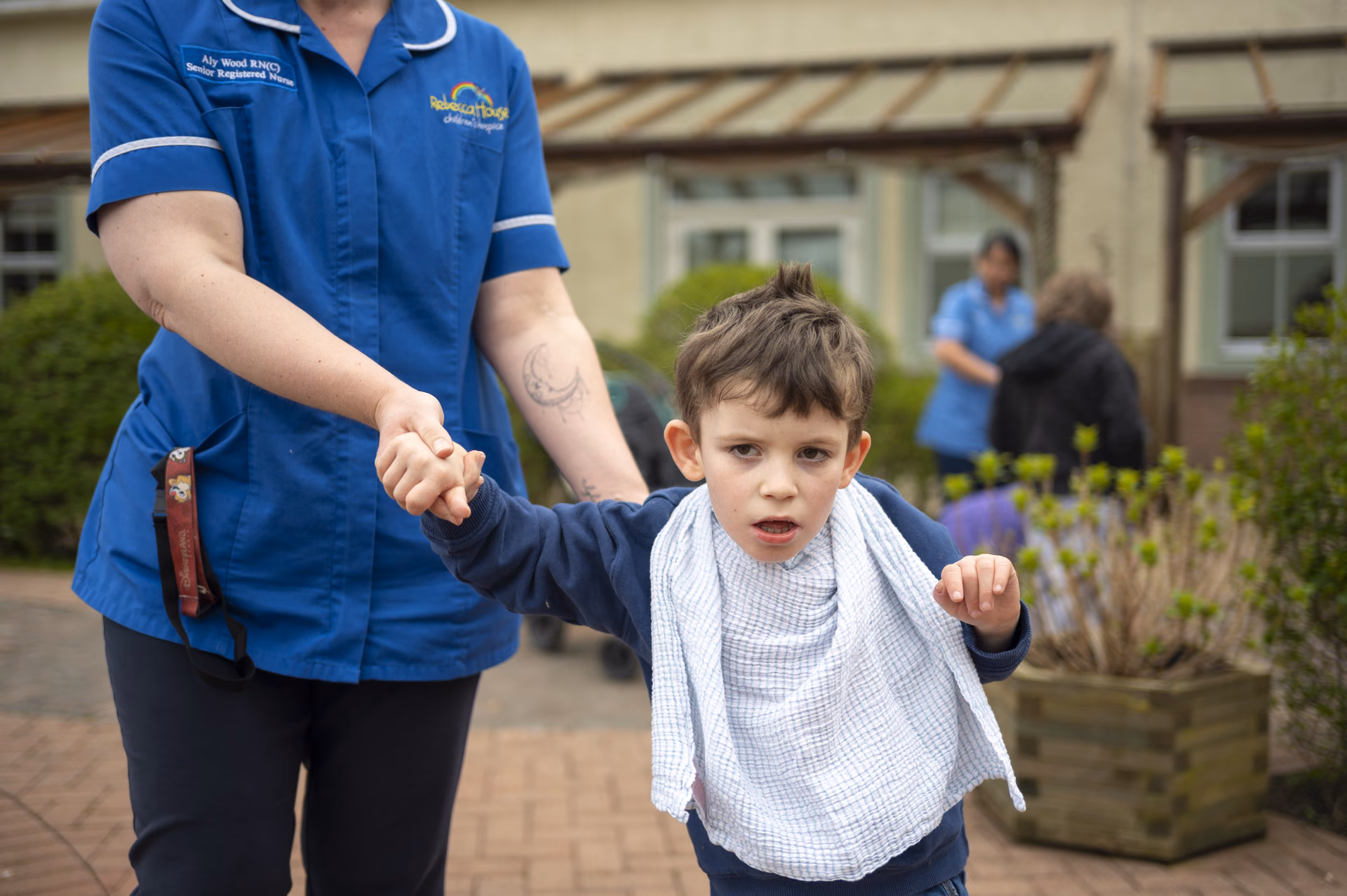 A Rebecca House nurse walking hand in hand with a boy