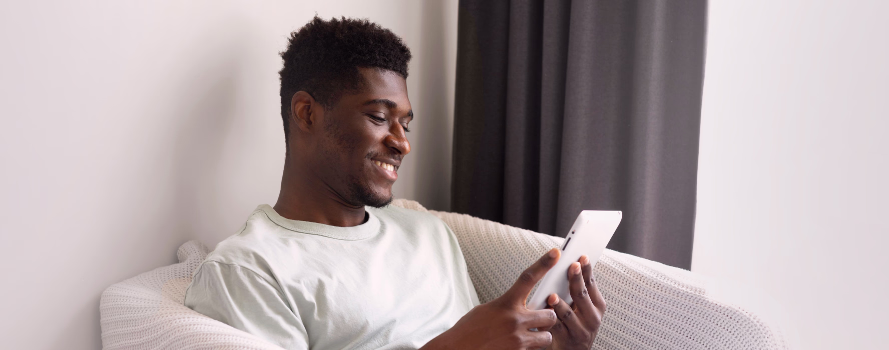 Man relaxing on a sofa while checking a tablet