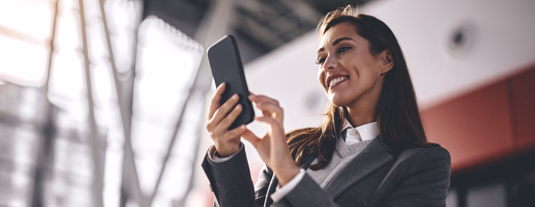 Businesswoman smiling at her phone in an airport terminal