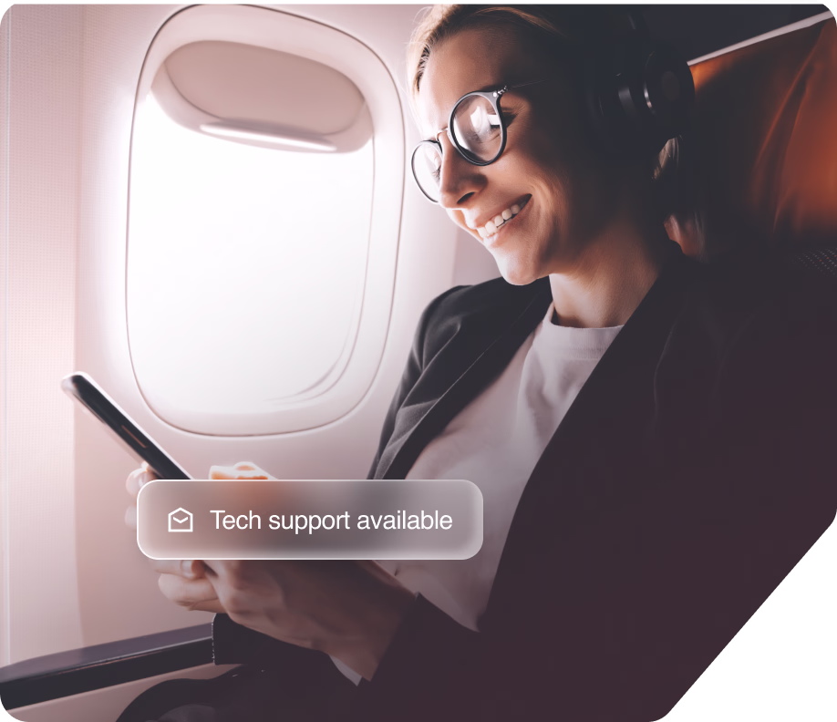 Passenger with headphones using a phone by the aircraft window