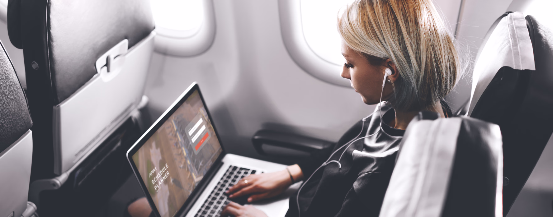 Passenger working on a laptop in an aircraft seat