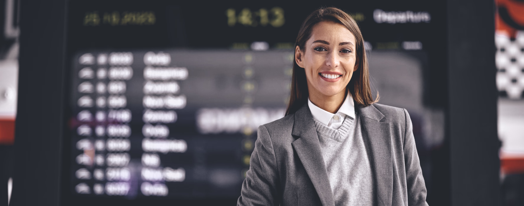 Smiling woman standing in front of an airport departures board