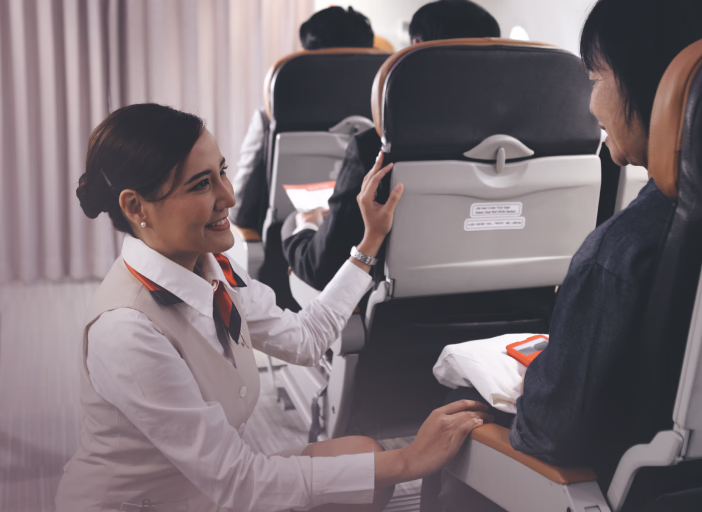 Flight attendant helping a passenger in the aircraft cabin
